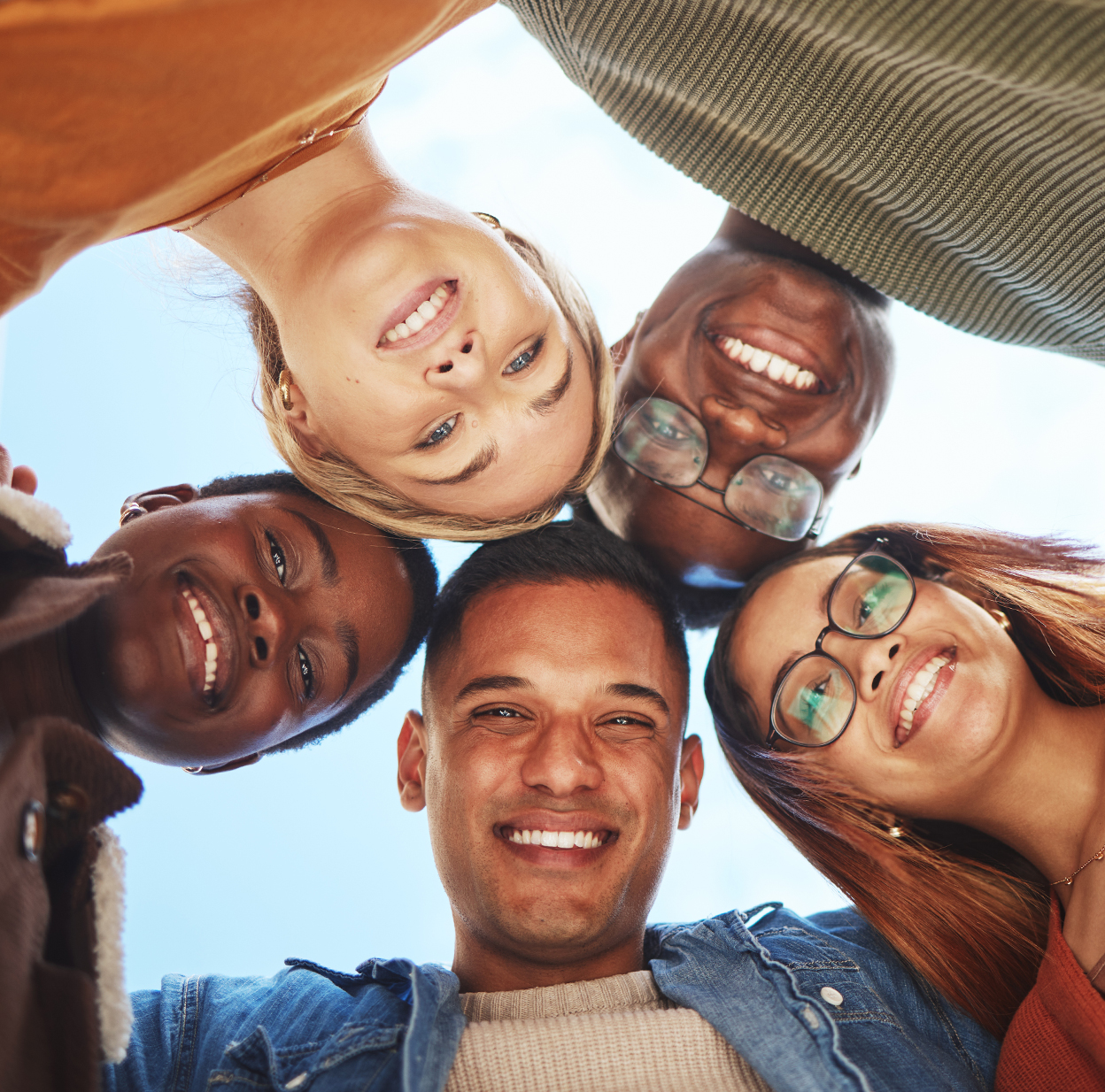 Cinco colegas de trabalho diversos sorrindo, olhando para a câmera.
