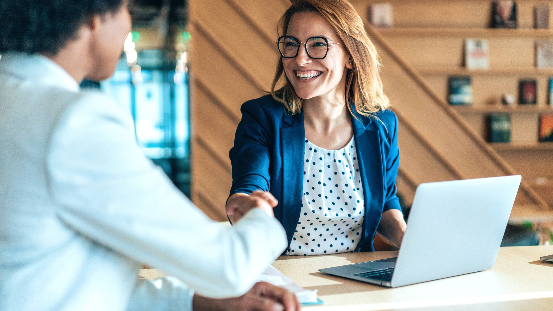 Dois profissionais de trabalho apertando as mãos em uma mesa.
