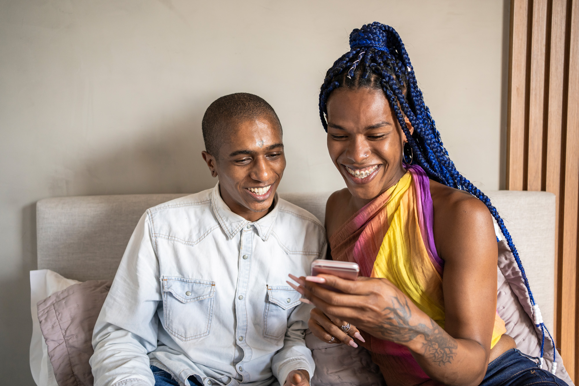 Duas pessoas sorrindo enquanto olham para um smartphone.