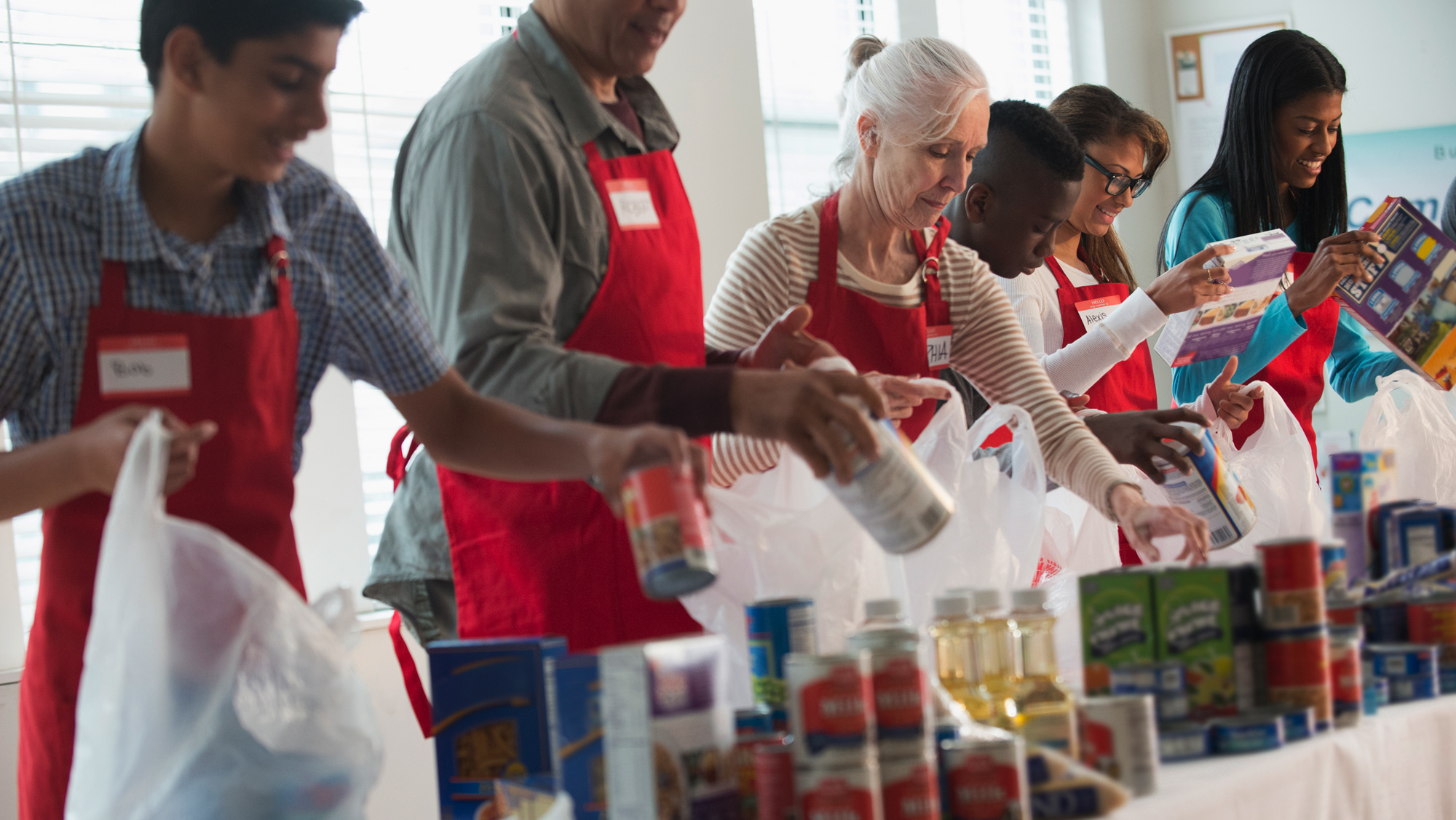 Voluntários de organizações sem fins lucrativos separam e embalam alimentos.