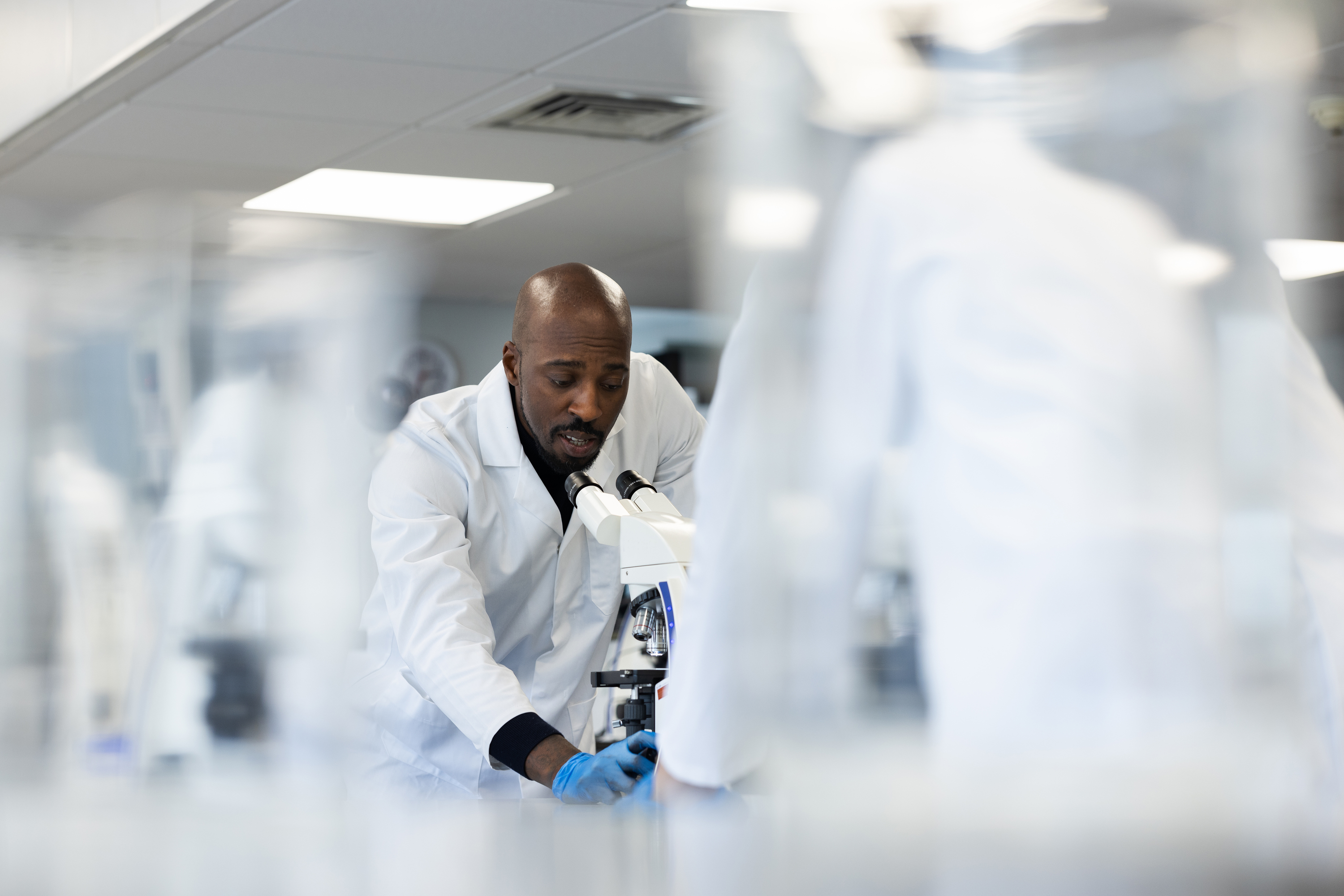 A scientist using a microscope in a lab.