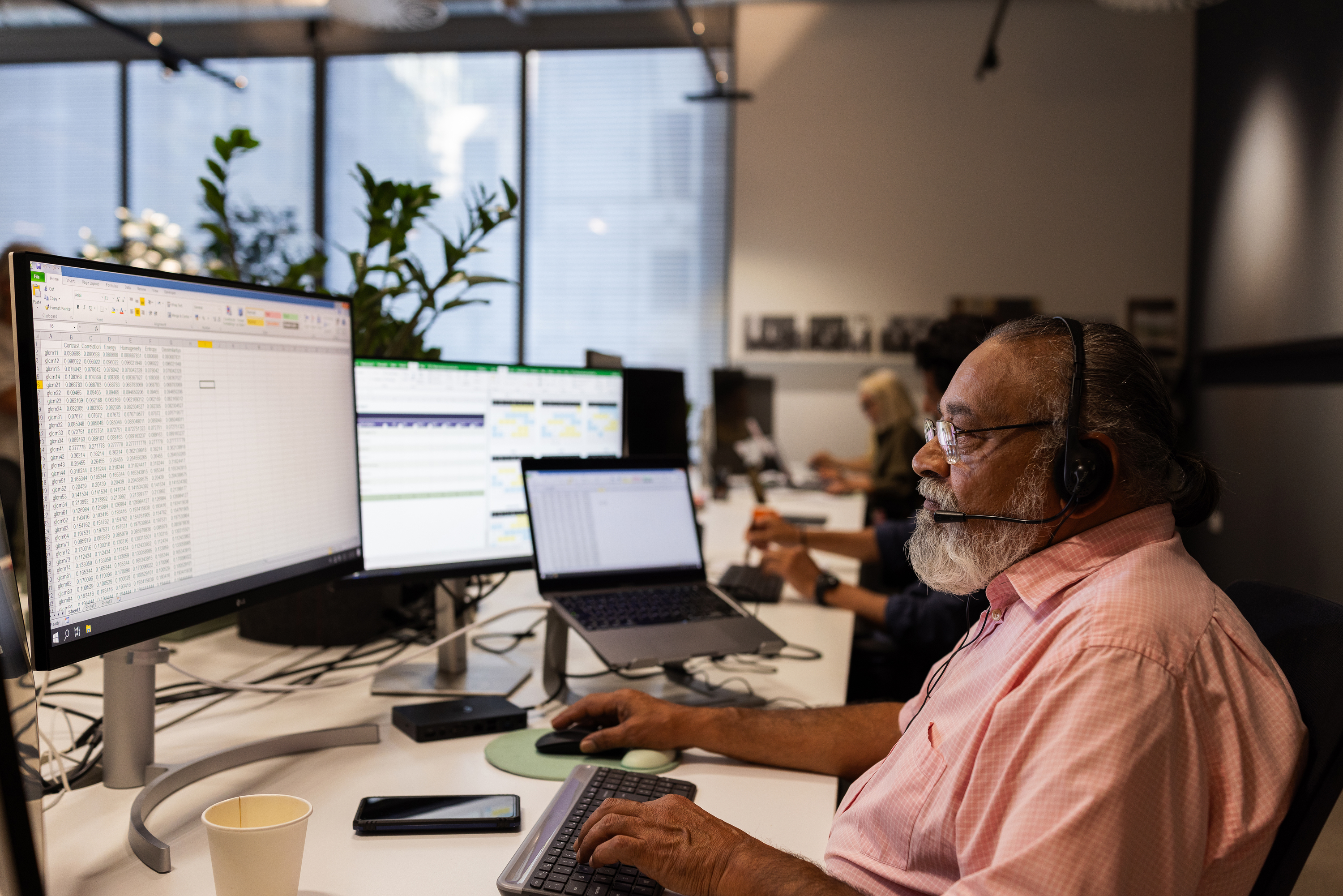 A man with a headset works at a computer.