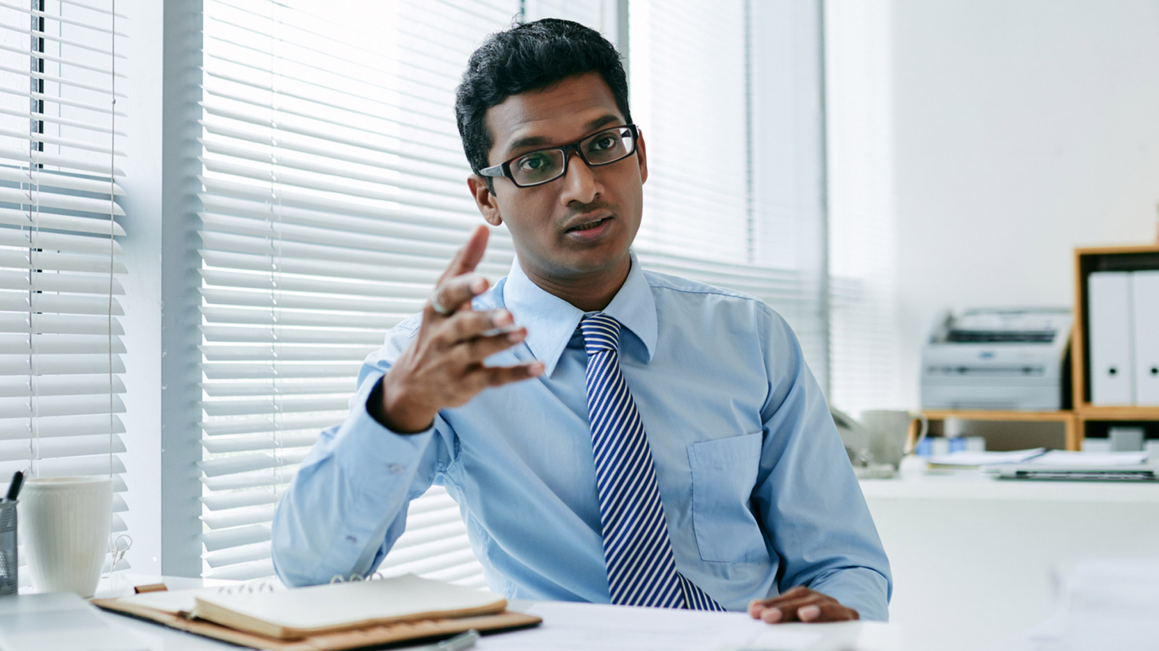 A businessman in a full-time position gestures while speaking.