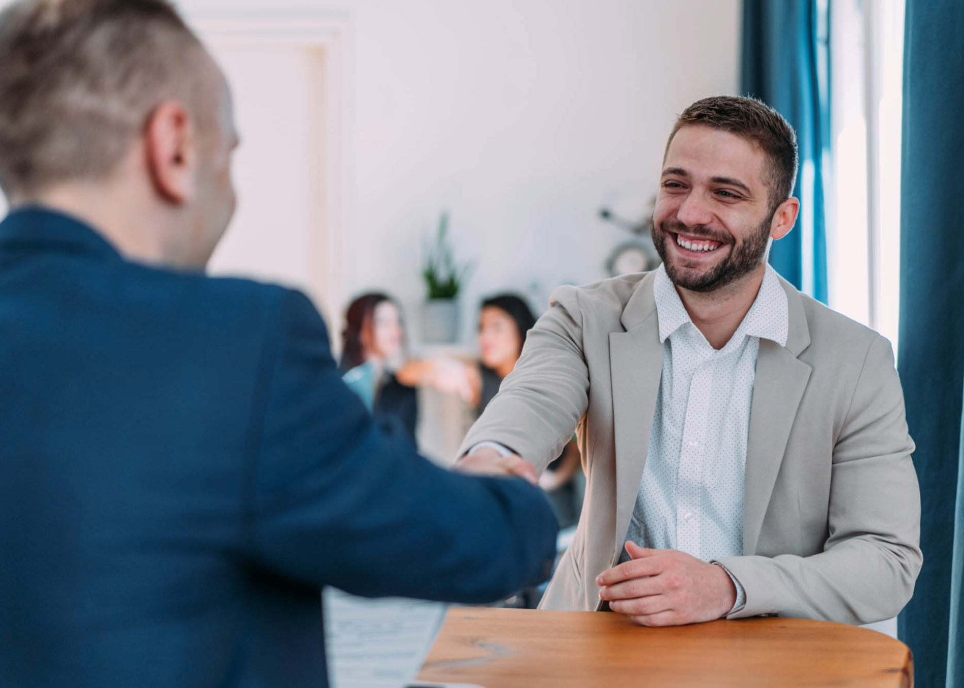 Smiling man shakes hands with another man.