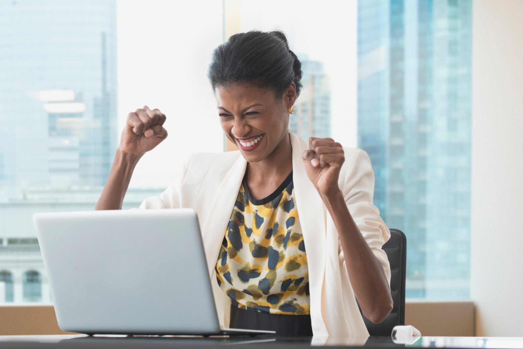 Uma empresária radiante celebra um sucesso em seu laptop.