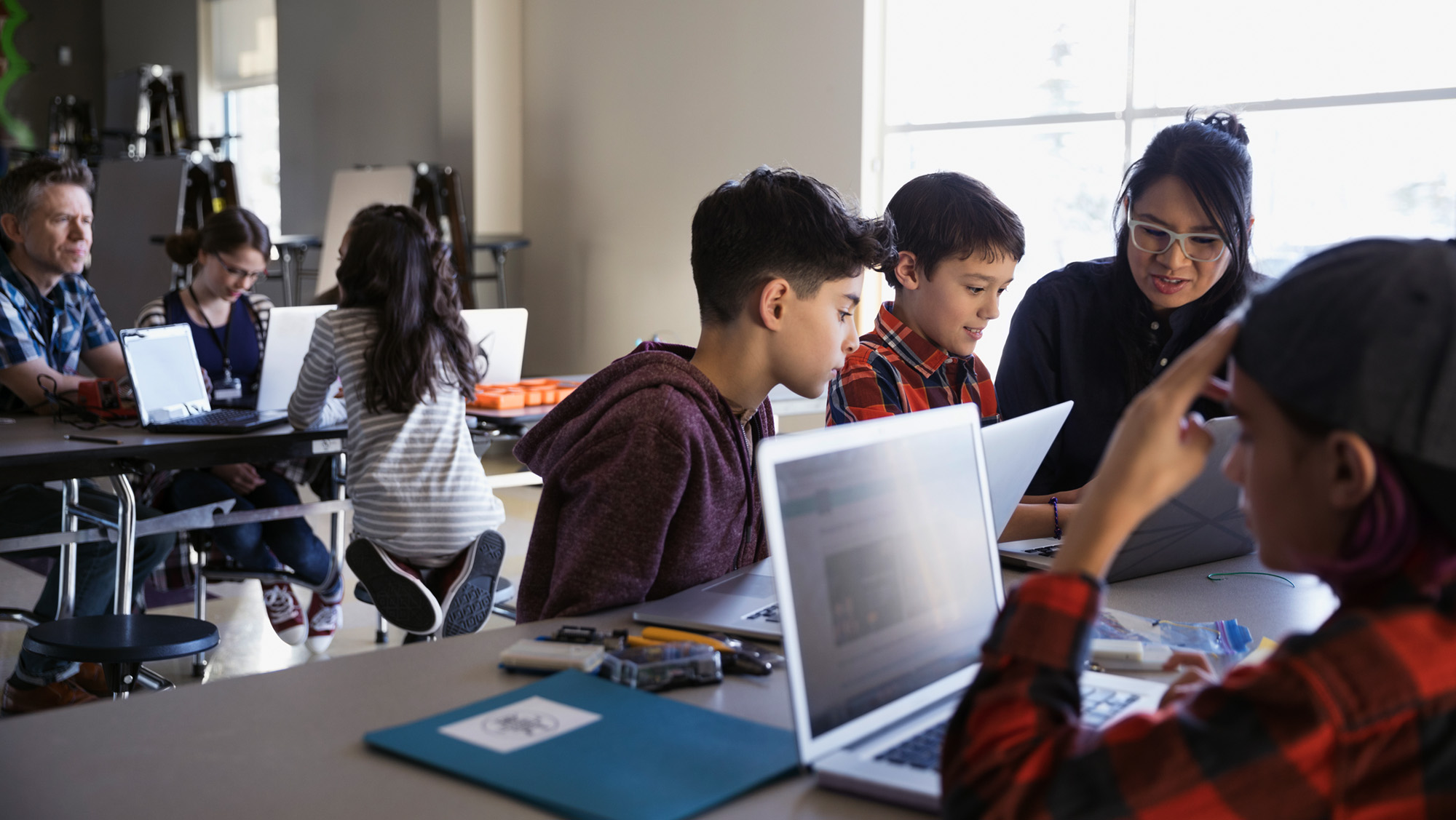 Alunos e adultos em uma sala de aula no local aprendendo juntos com computadores.