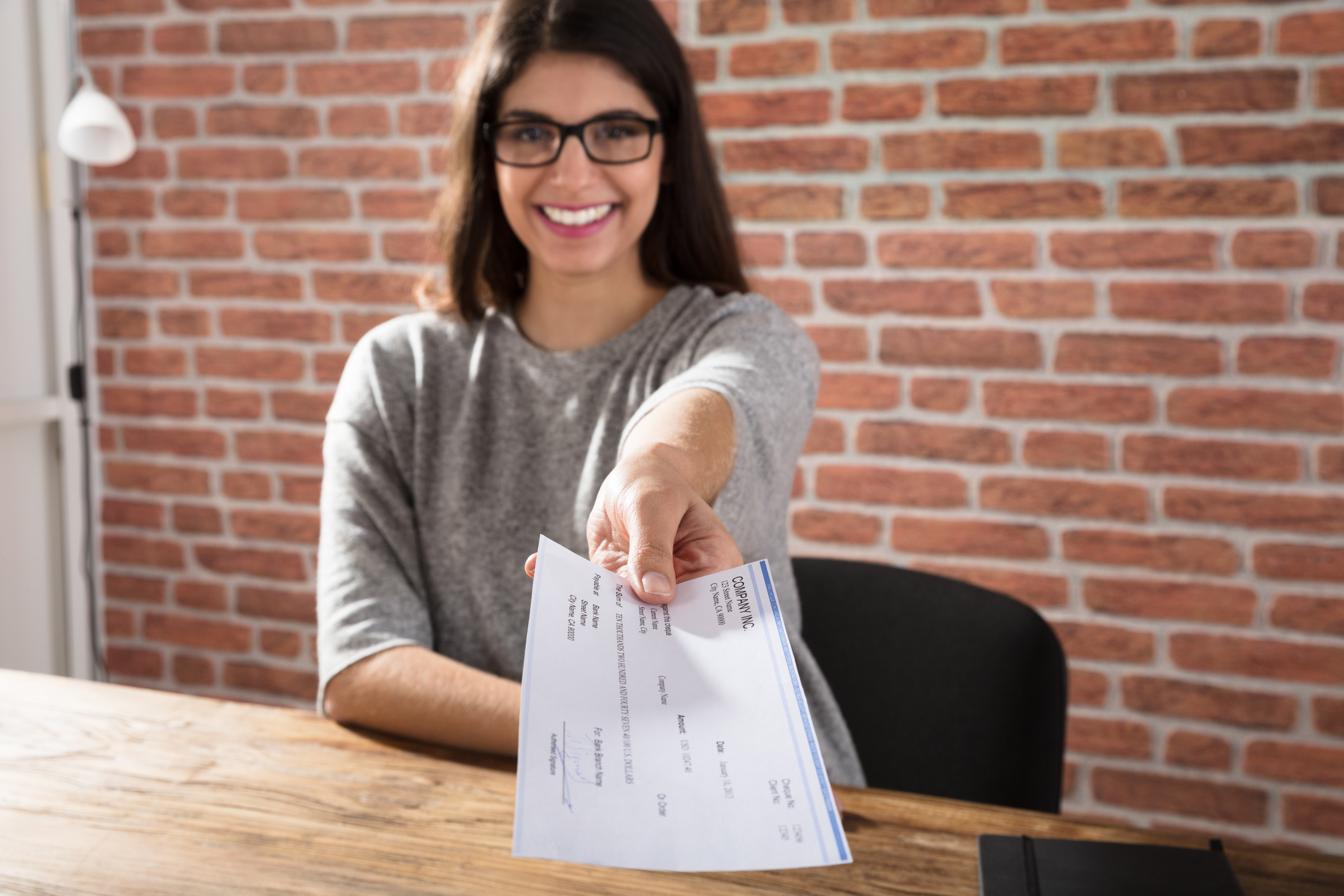 Mulher sorridente oferecendo um contracheque.