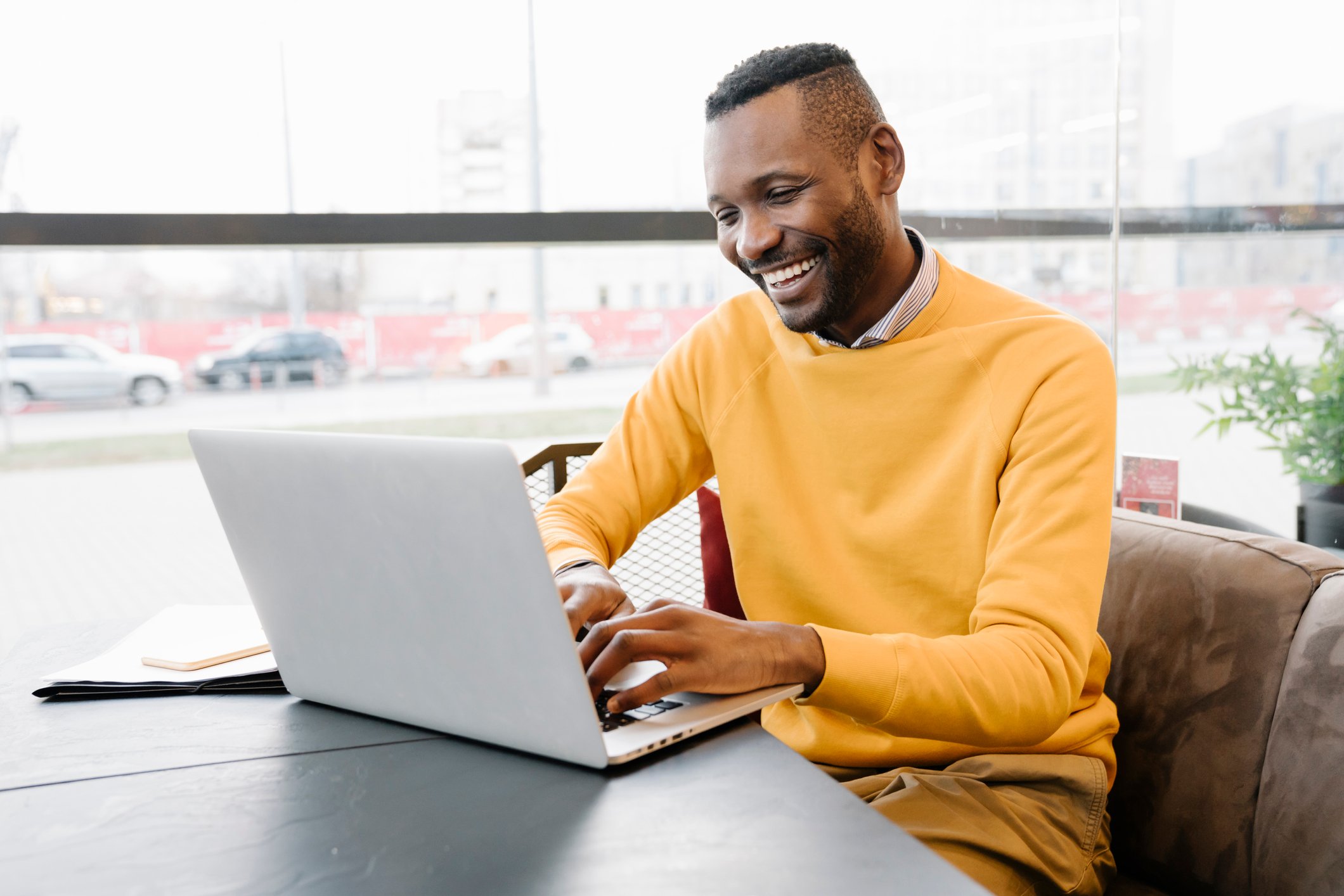 Homem sorridente usando um notebook.