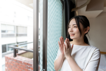 Uma mulher com uma expressão feliz perto de uma janela.