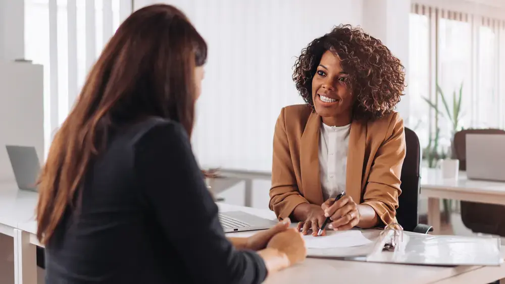Two women smiling during a meeting.
