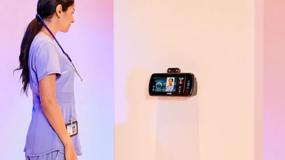Nurse facing a wall-mounted touchscreen device.
