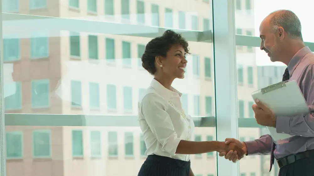 Two businesspeople shaking hands in an office.