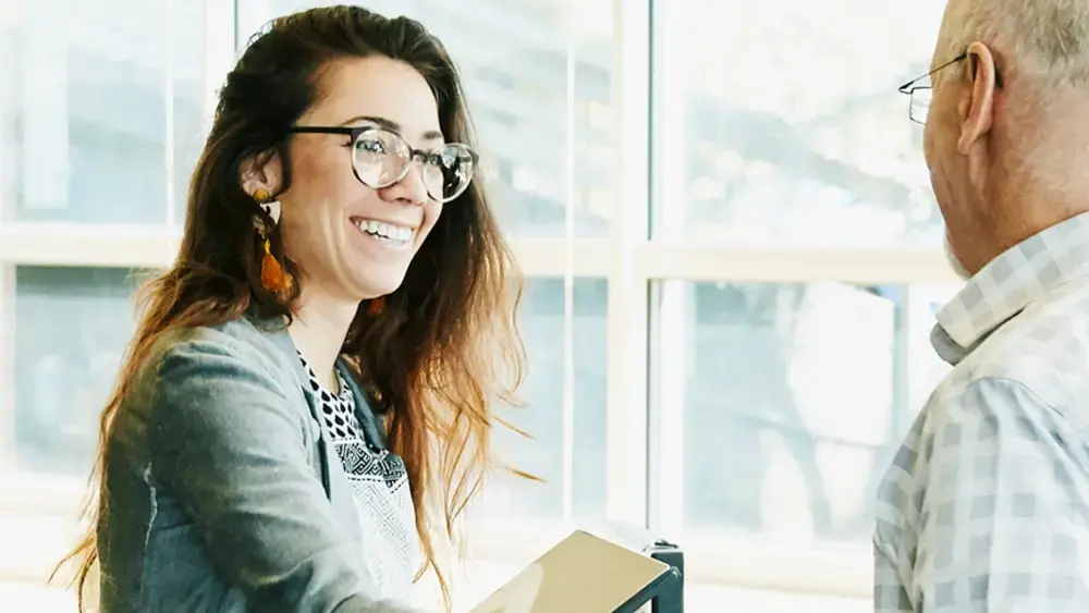 Smiling coworkers shaking hands in an office.
