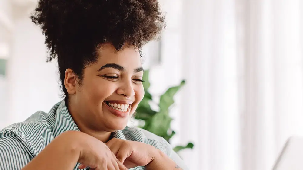 Online businesswoman smiles while working on her laptop.