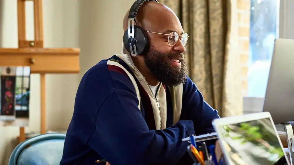 A man with a headset on, working from home on a laptop.