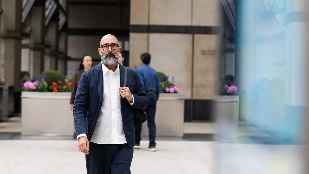 A man in a suit walks past an office building.