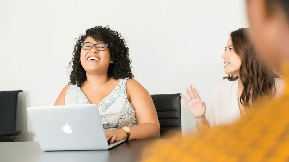 A women laughs while chatting with her colleagues.