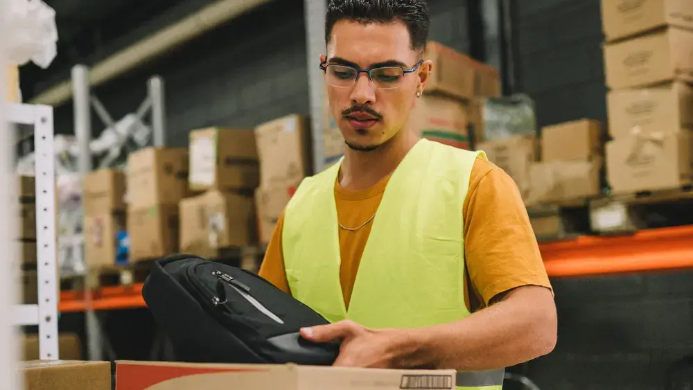 Warehouse worker placing a bag in a box.