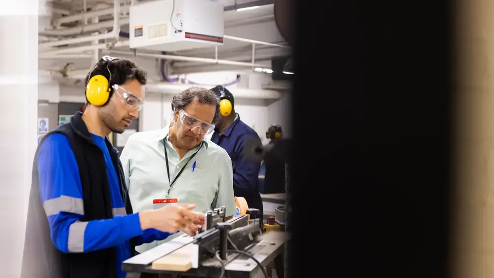 Workers wearing hearing protection operate machinery.