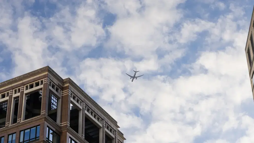 Airplane flying over city buildings.