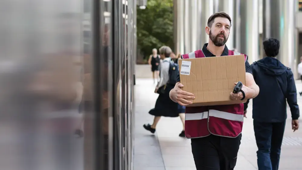 A delivery person walks on-site with a box in hand.