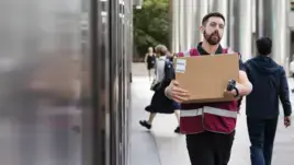 A delivery person walks on-site with a box in hand.