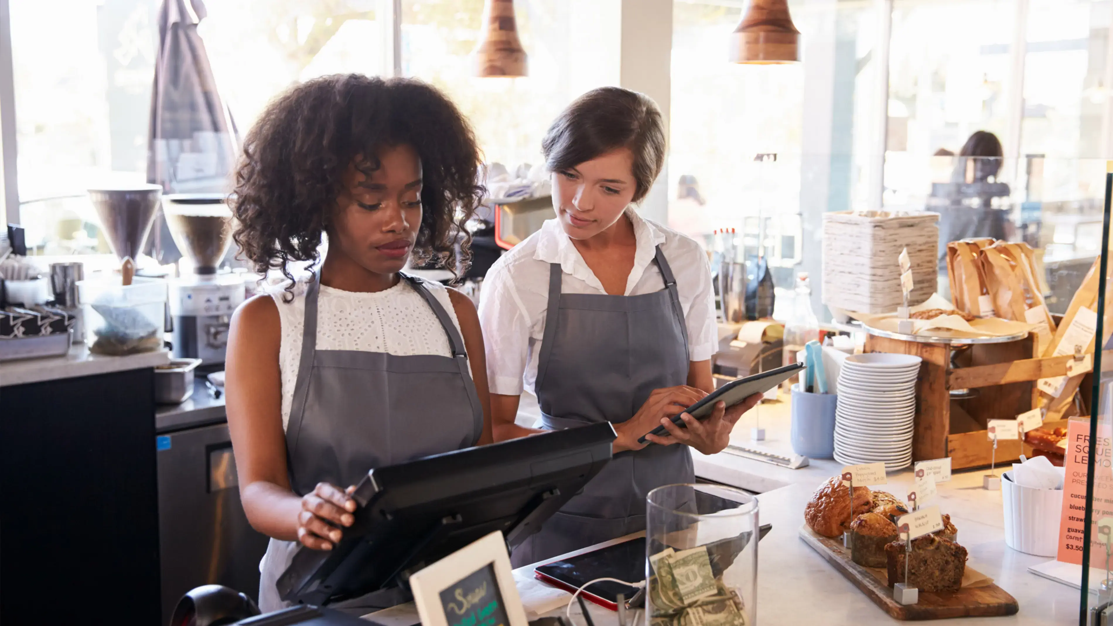 Dois colegas de trabalho trabalham juntos em uma lanchonete. Um deles é caixa.