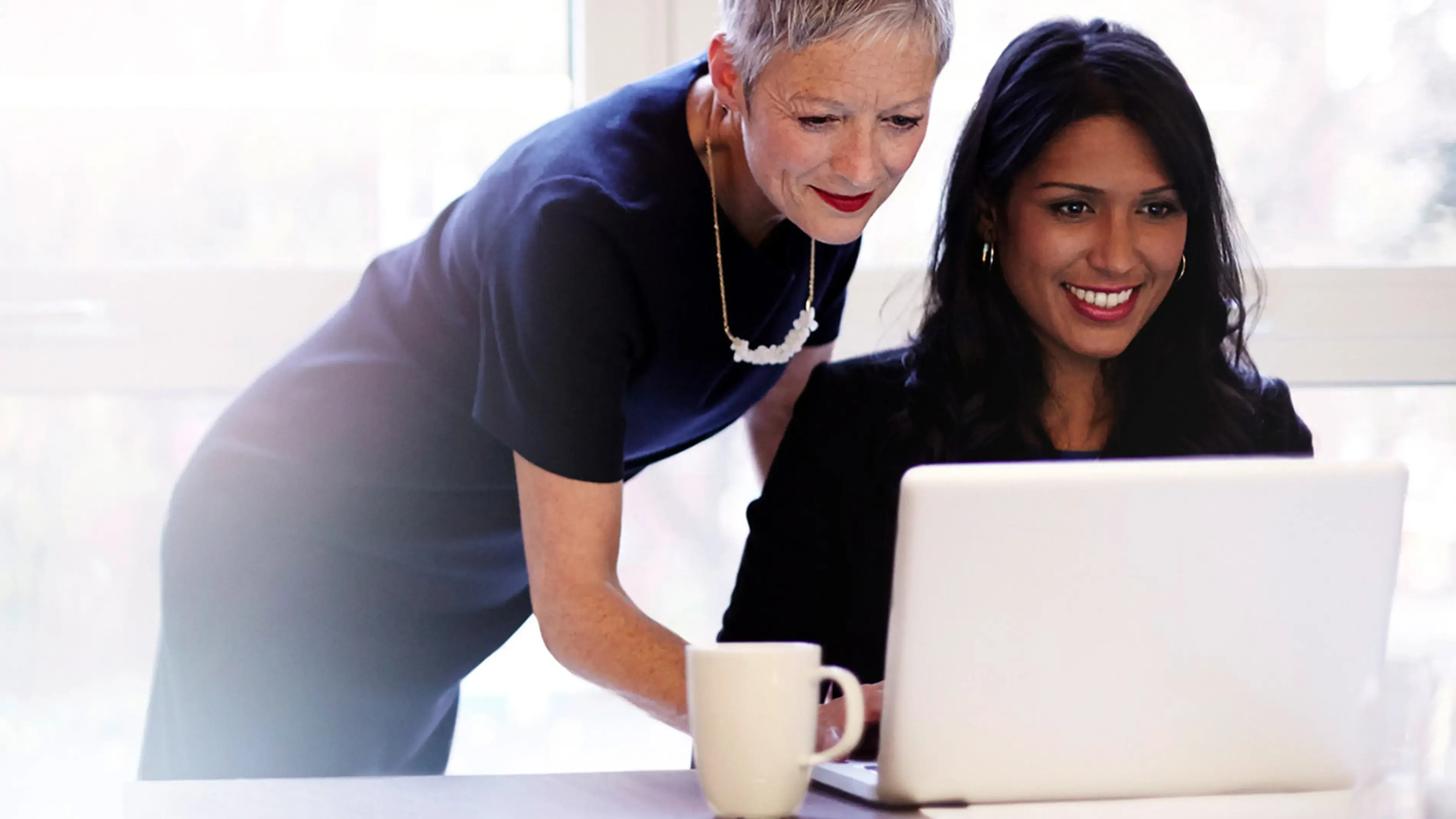 Two coworkers looking at a laptop together.