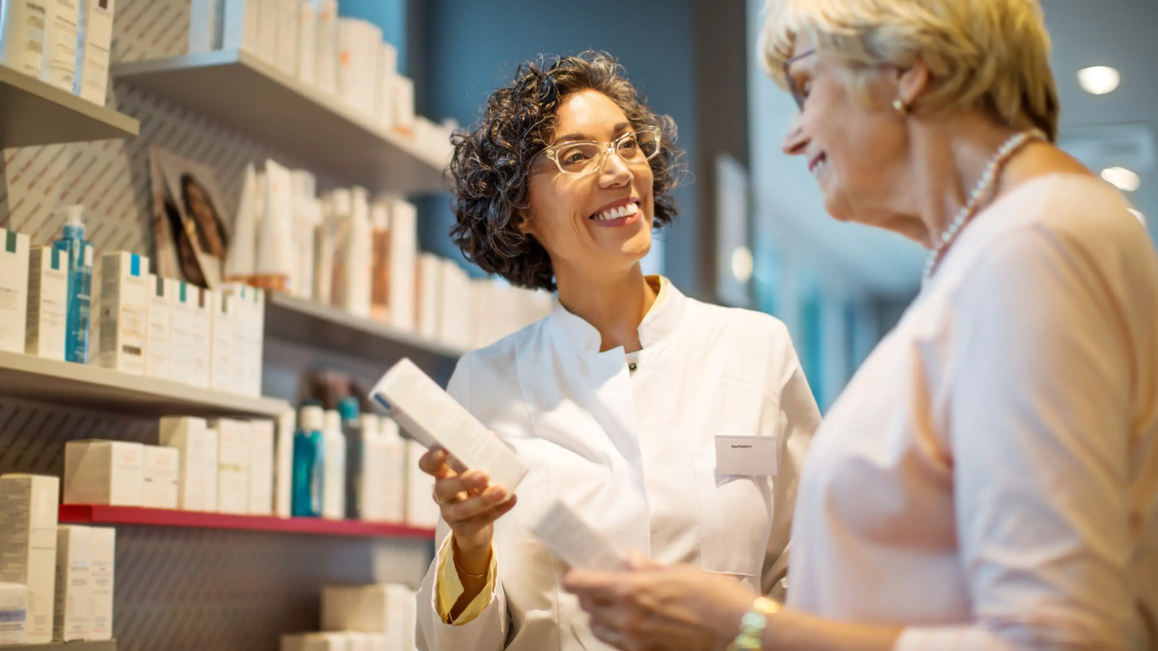 Funcionário de loja auxiliando um cliente na compra de um produto para a pele.