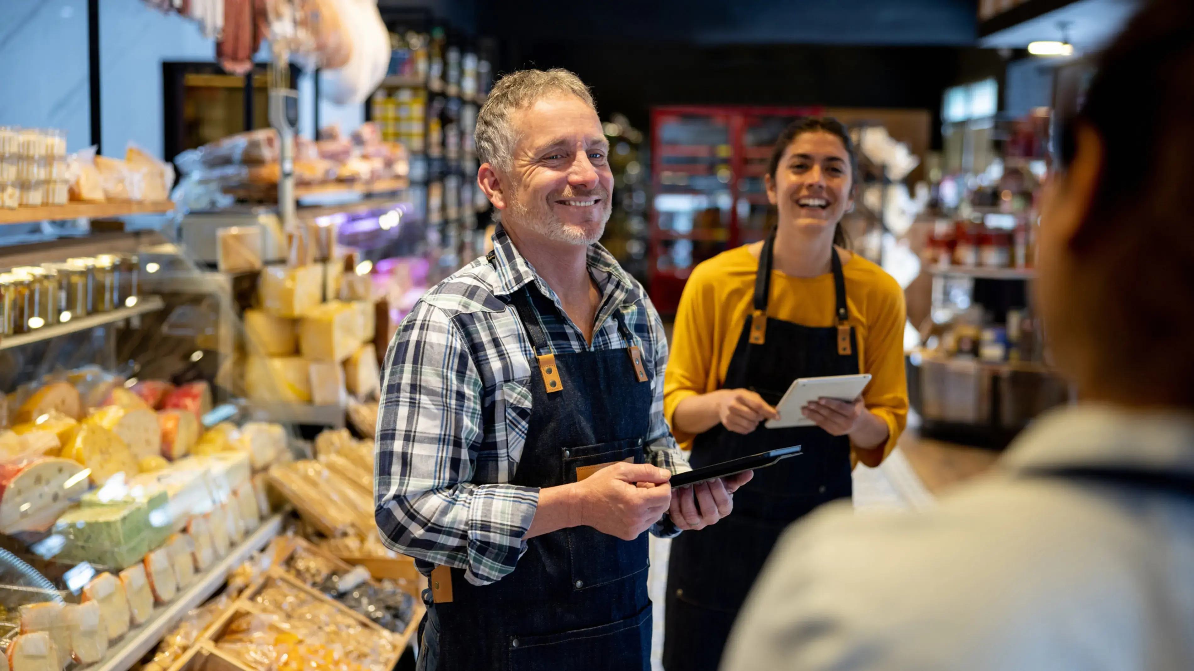 O dono de uma delicatessen e colegas de trabalho ajudando um cliente.