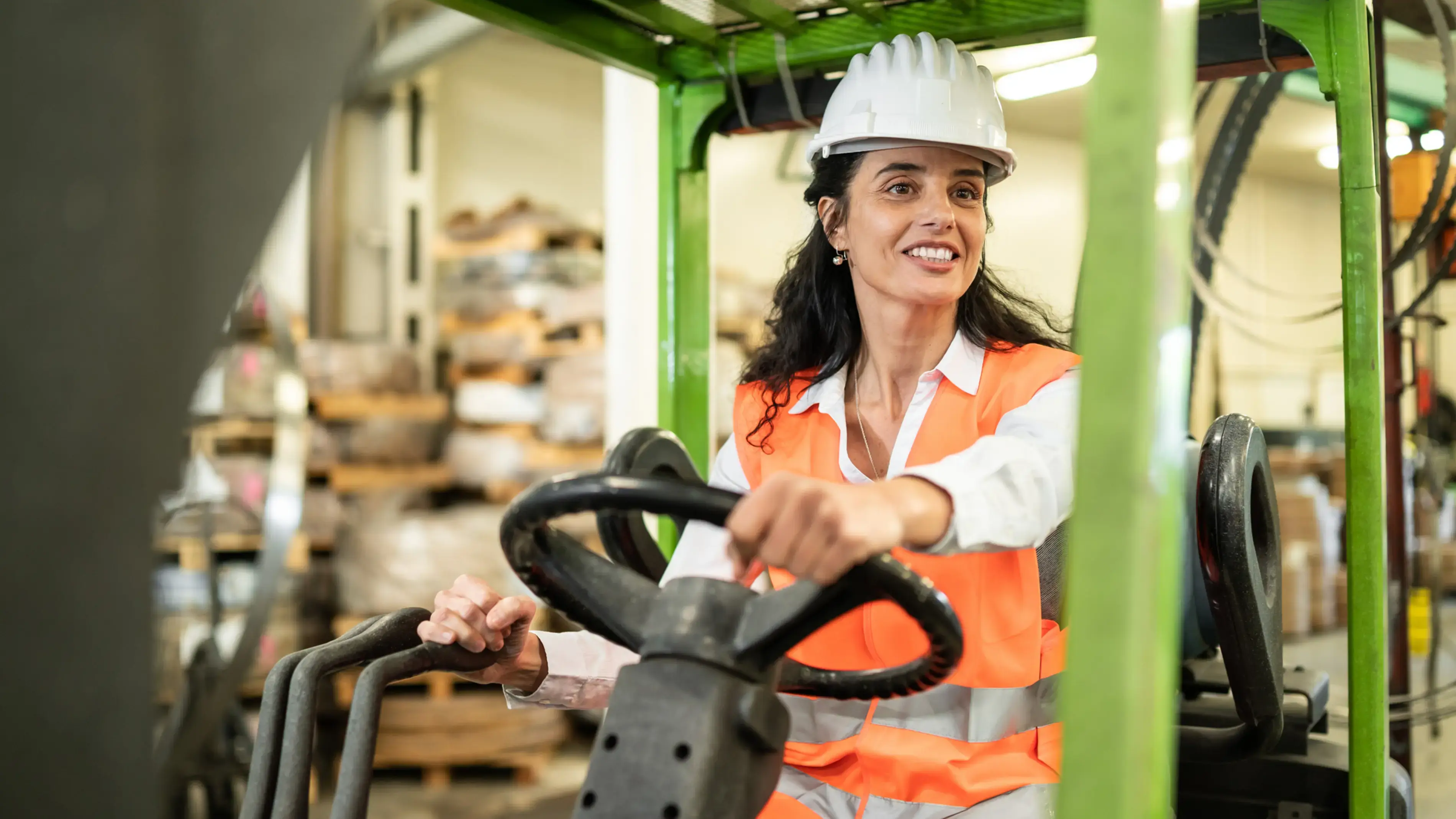 A smiling employee operates a forklift in a warehouse.