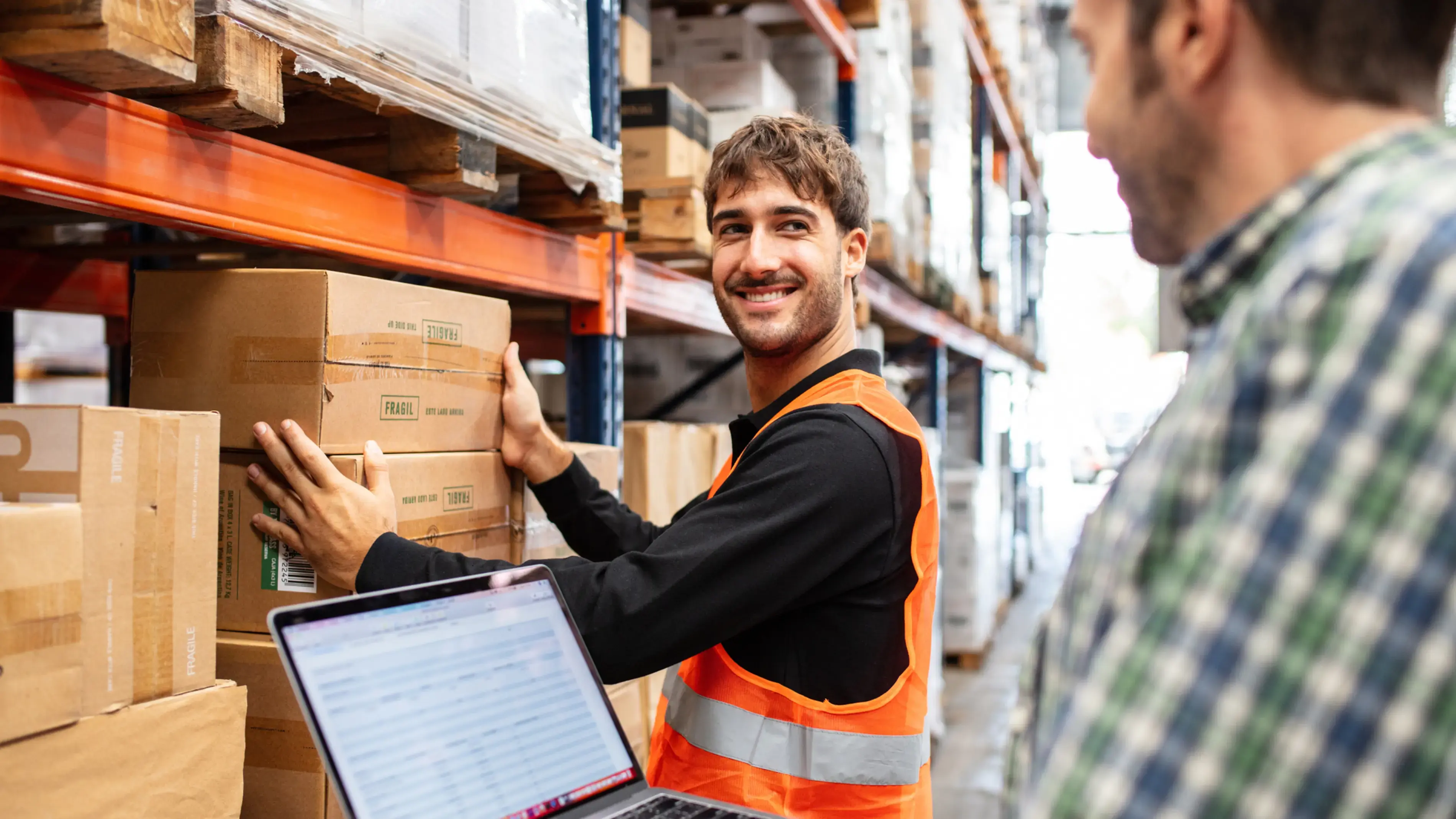 A coworker smiling while working in a warehouse.