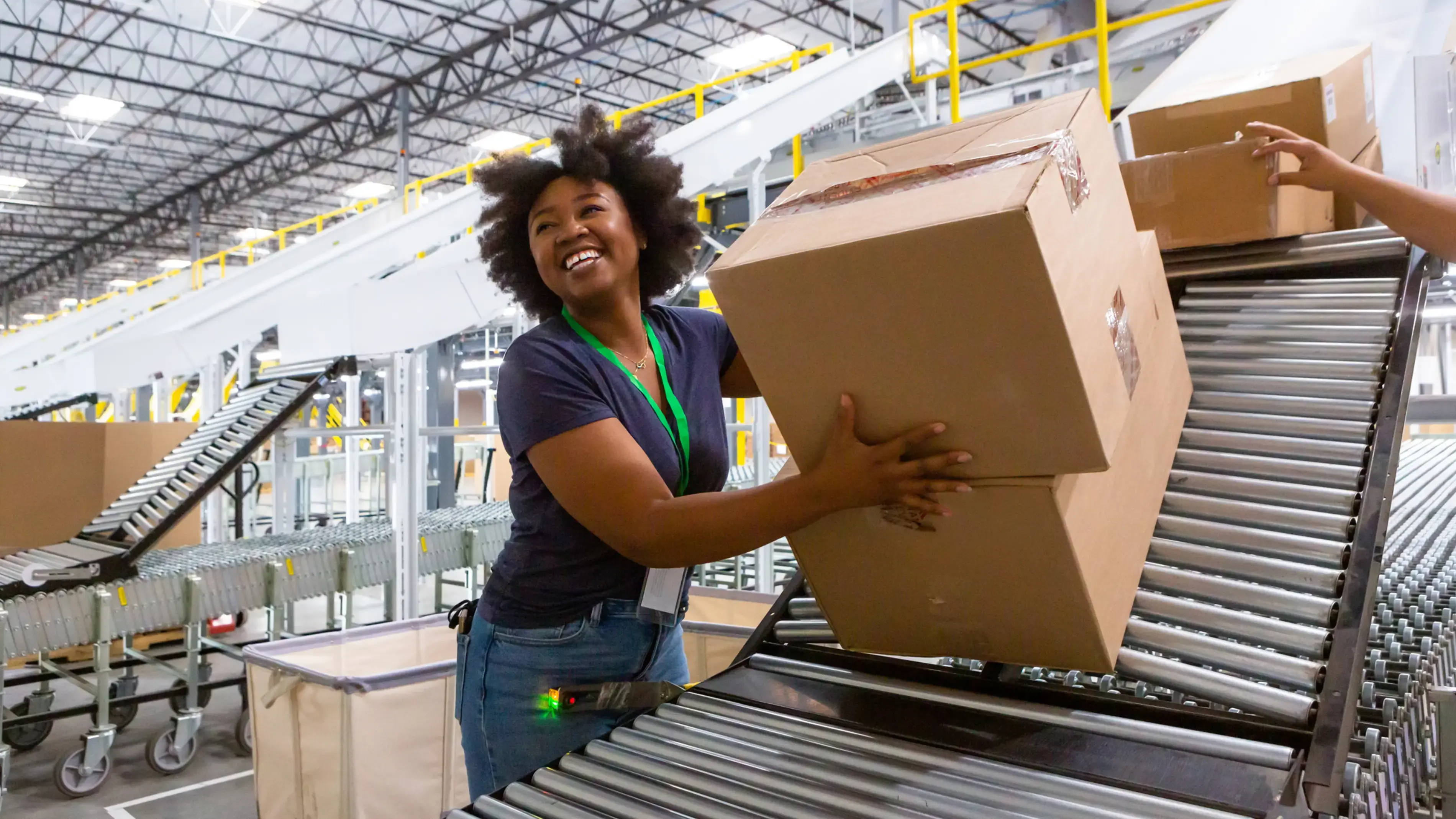 An employee places a box on the conveyer belt in a warehouse.