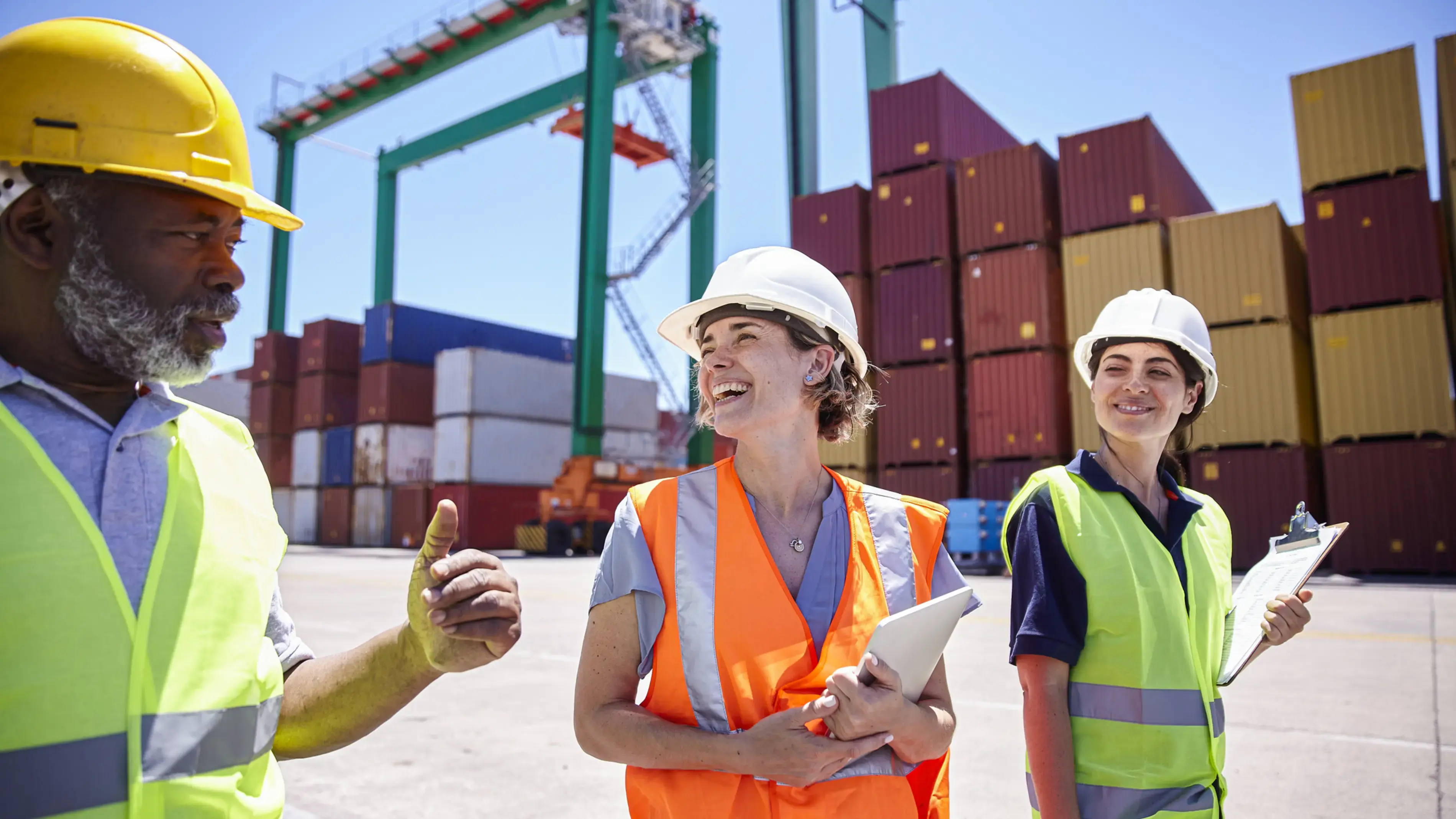 Three coworkers at a port discussing the workflow of shipping containers.