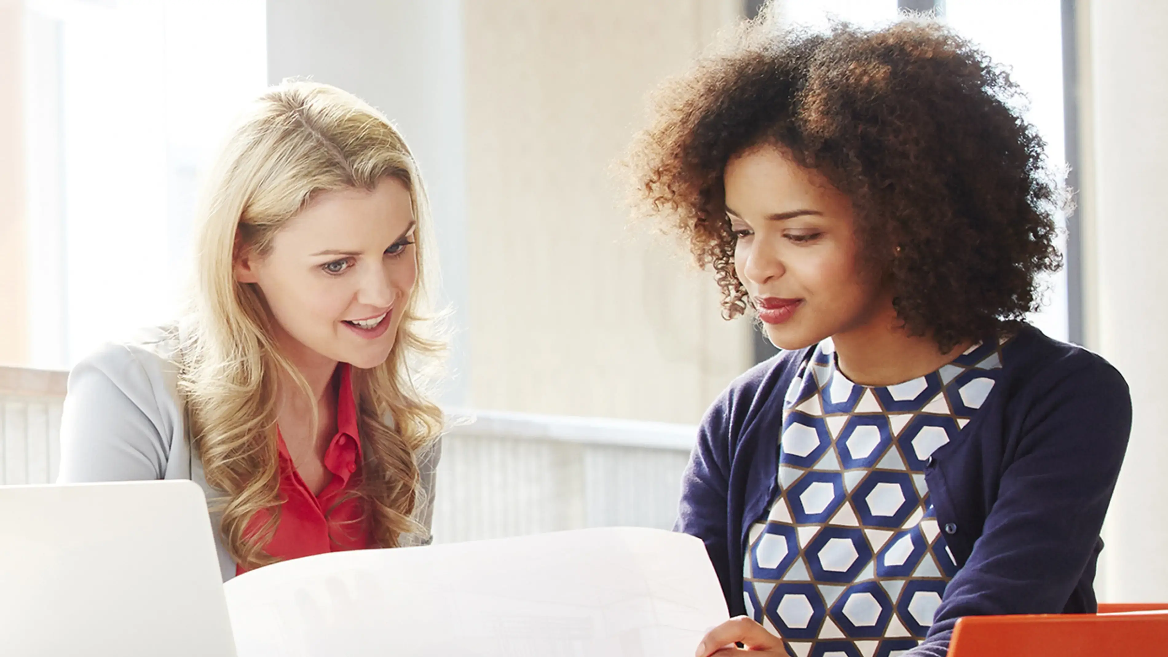 Two coworkers review the white paper together.