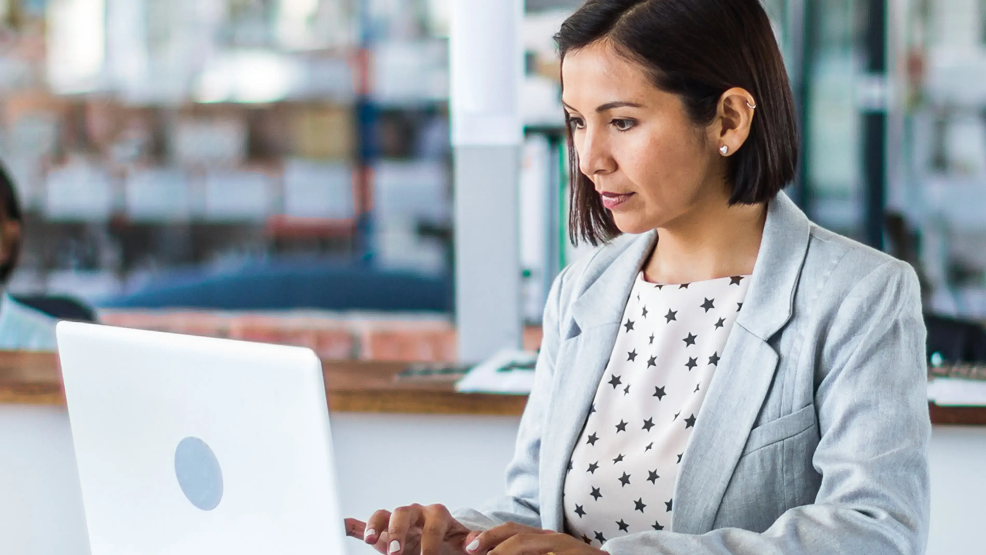 Uma funcionária trabalha em seu laptop em uma mesa.