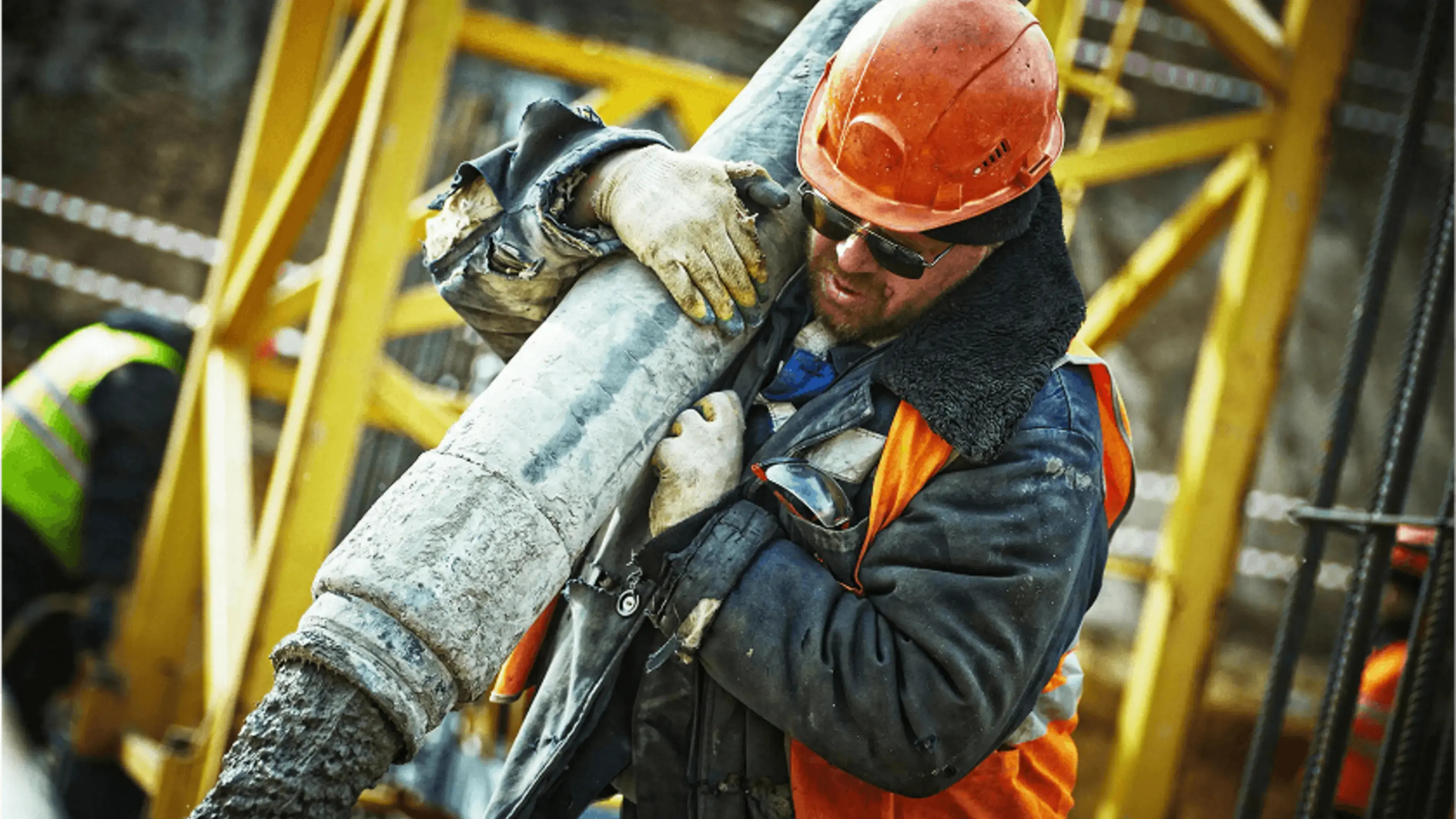 Construction worker carrying a heavy pipe.