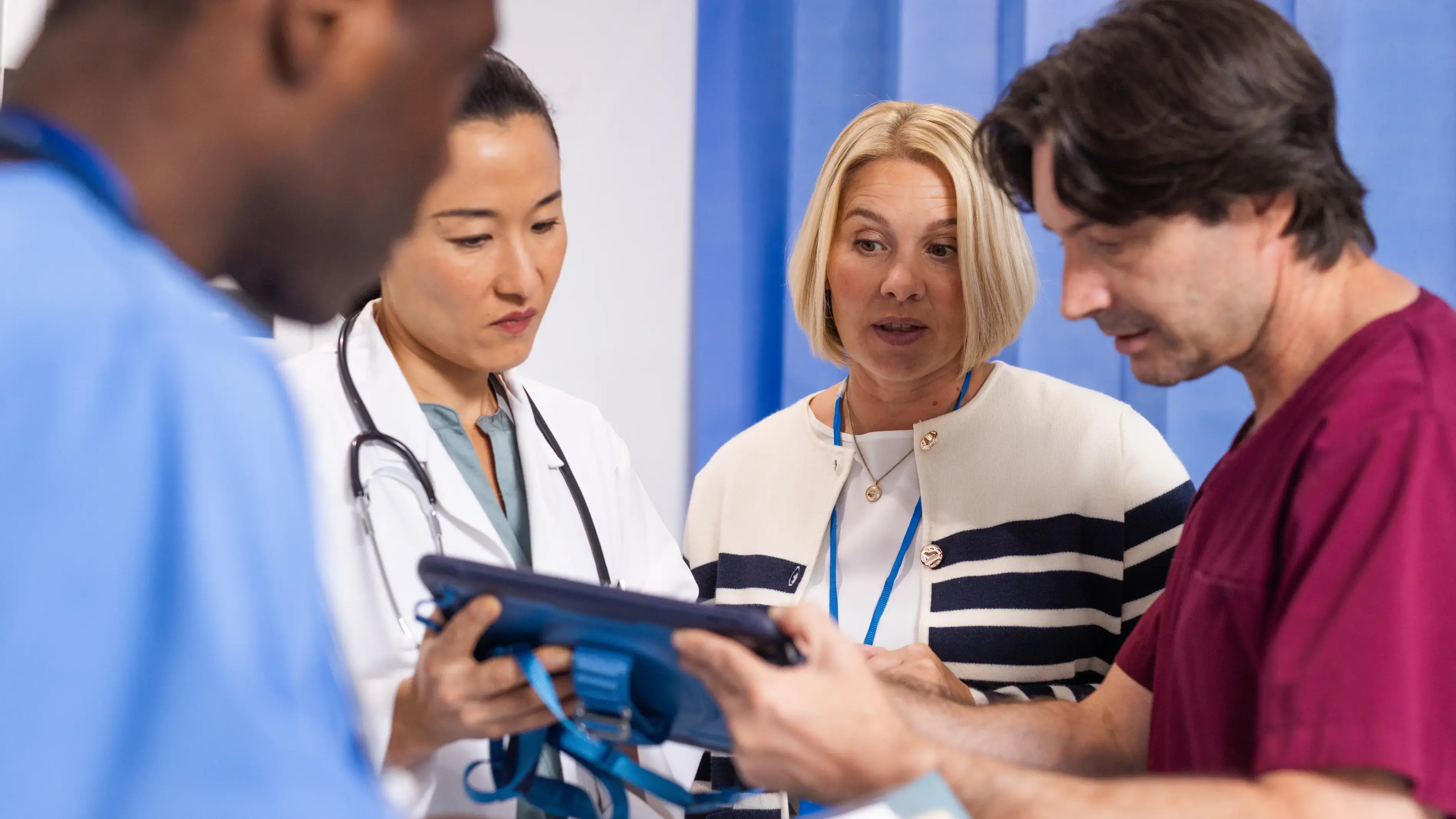 A healthcare team reviews a tablet.