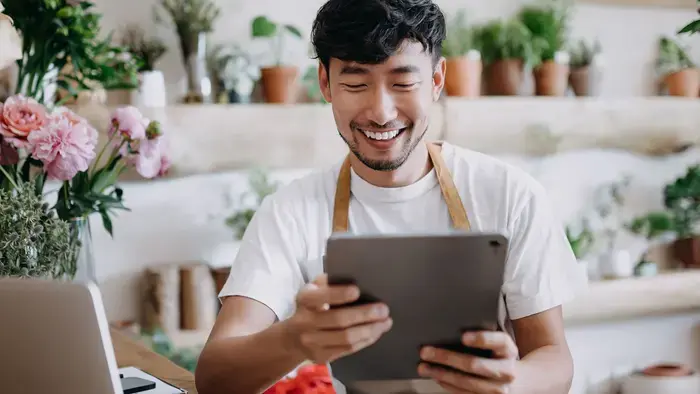 Smiling man using tablet in flower shop.

