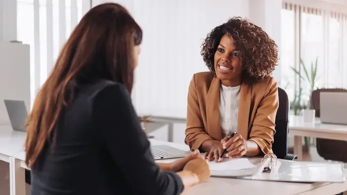 Two women smiling during a meeting.
