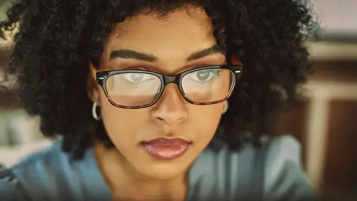 A woman with glasses looks intently at a touchscreen.