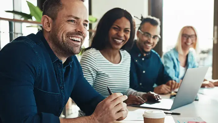 A cross-functional team of coworkers smiles in a meeting.