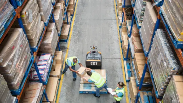 Workers load packages in an industrial warehouse, a workflow in action.