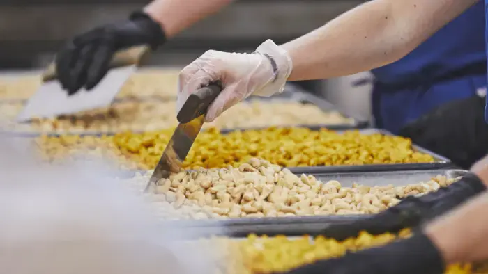 Employees using tools to prepare food products.