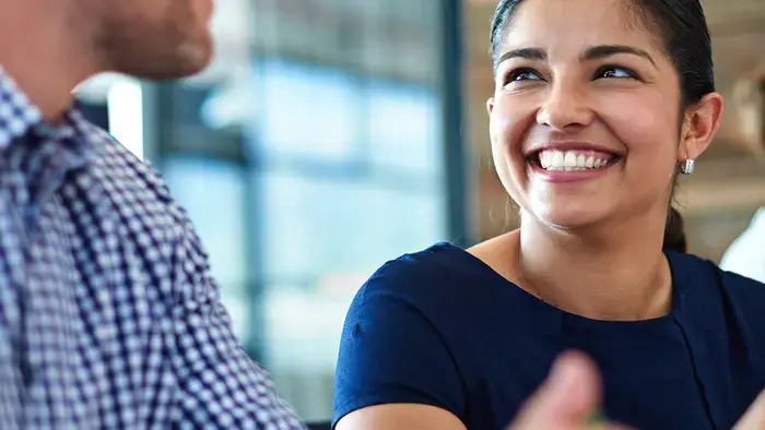 Uma mulher sorri enquanto conversa com um colega de trabalho.