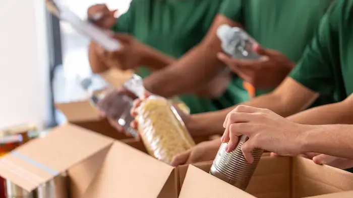 Os voluntários organizam os alimentos em caixas para distribuição.