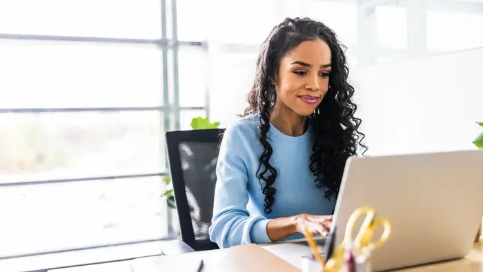 Woman working on laptop at a desk; on-site.