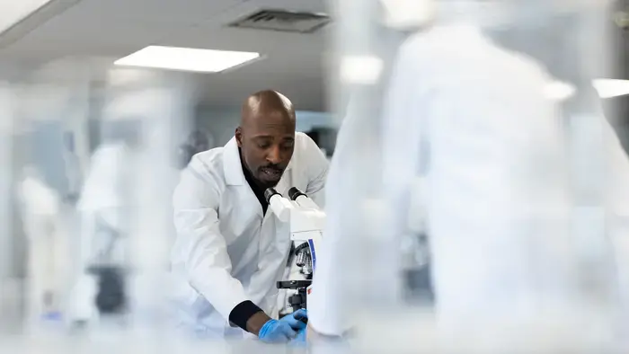 A scientist using a microscope in a lab.