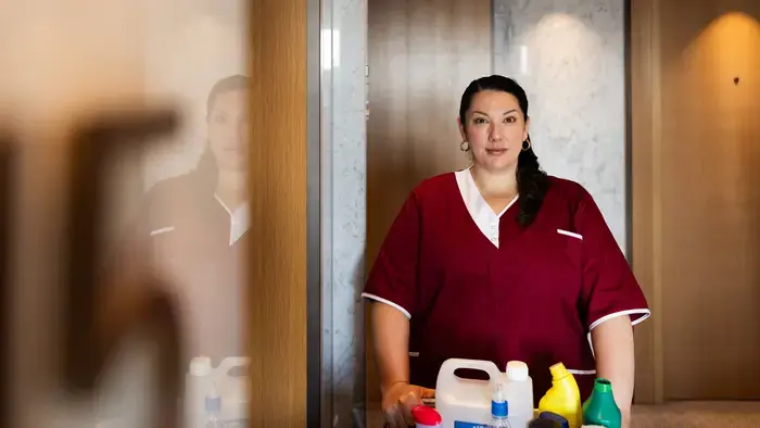 Hotel housekeeper standing by a cleaning cart.