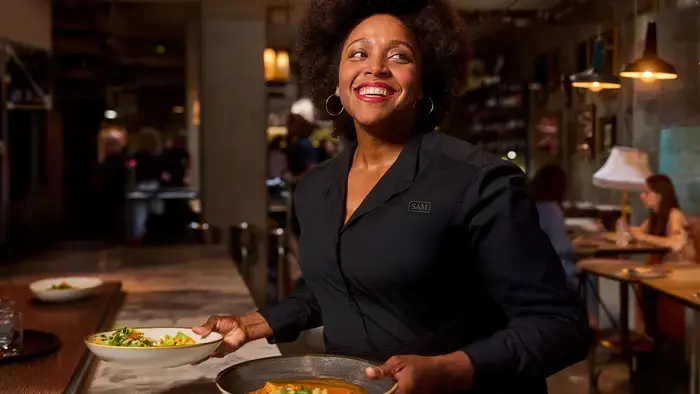 Smiling server carrying two plates of food.
